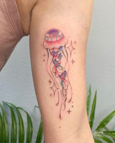 a woman's thigh with a tattoo of a jellyfish and stars on it