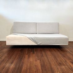 a couch sitting on top of a wooden floor next to a white wall and hardwood floors