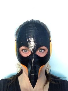 a woman wearing a black mask with orange strips on her face and the bottom half of her mouth