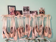 several pairs of ballet shoes hang on a rack in front of pictures and photos hanging on the wall