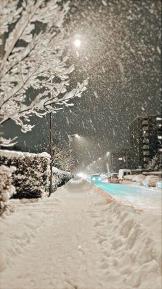 the snow is falling and there are cars parked on the side of the snowy road