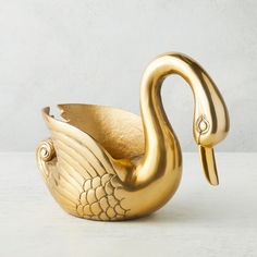 a gold swan figurine sitting on top of a white table next to a wall