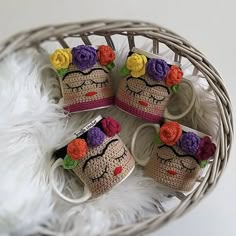 three crocheted mugs with flowers on them sitting in a wicker basket