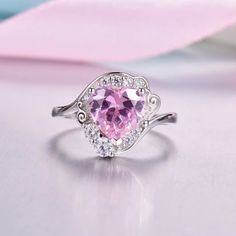 a pink heart shaped ring with diamonds around it