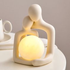 a white table topped with a light and a couple figurine sitting on top of it