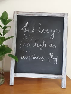 a chalkboard with writing on it next to a potted plant