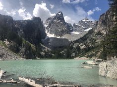 a mountain lake surrounded by trees and rocks with snow on the mountains in the background