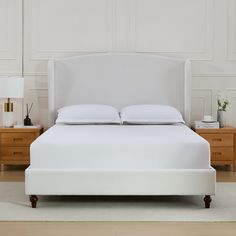 a white bed with two nightstands and a night stand in front of the bed