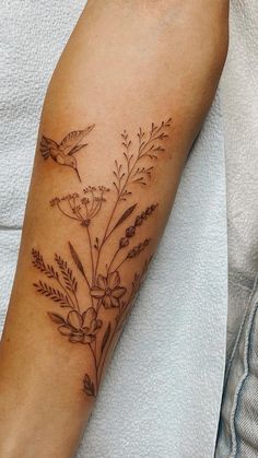 a person with a tattoo on their arm that has flowers and birds flying around it