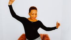 a woman sitting in a chair with her arms up