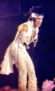 michael jackson performing on stage in white outfit and headpiece with microphone to his side