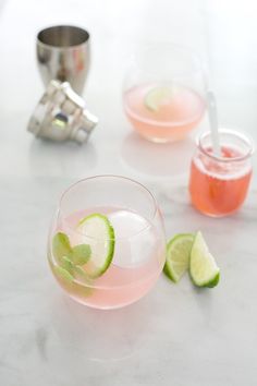 three glasses filled with different types of drinks on top of a white marble countertop