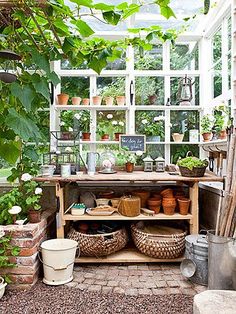 an outdoor greenhouse with potted plants and pots on the shelves in front of it