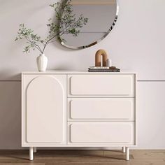 a white dresser with a round mirror above it