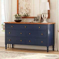 a blue dresser with two vases on top of it in front of a mirror