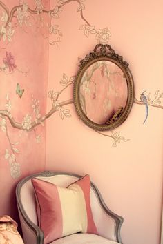 a chair and mirror in a room with pink walls