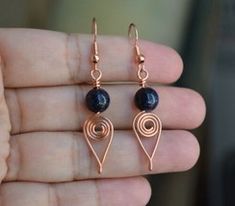 a pair of earrings that are on someone's finger in their hand, with blue beads