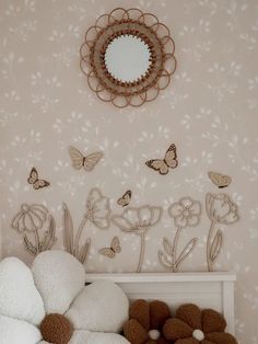 a white bed topped with pillows next to a mirror and butterflies on the wall behind it