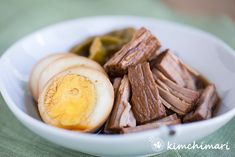 a white bowl filled with meat and an egg on top of green table cloths