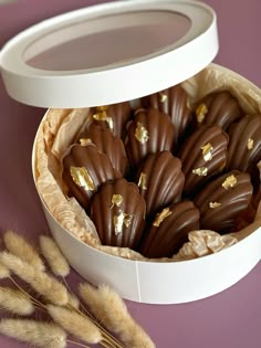 there are chocolates in the box and some dry grass next to it on the table