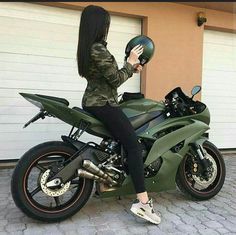 a woman sitting on top of a green motorcycle