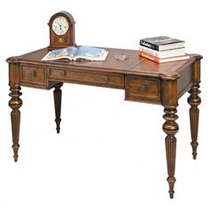 a wooden desk with a clock and books on it