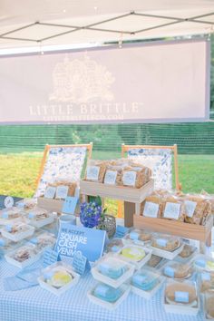 a table topped with lots of food under a white and blue tented awning