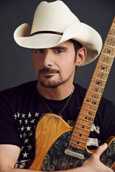 a man wearing a cowboy hat and holding an electric guitar in front of his face