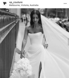 a woman in a white dress is walking down the street with her veil over her head