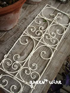 an iron gate sitting on top of a wooden table next to a potted plant