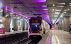 a subway train pulling into the station with people waiting on the platform to board it