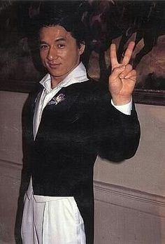 a man in a black and white suit making the peace sign