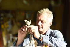 a man sitting at a table holding a small bird