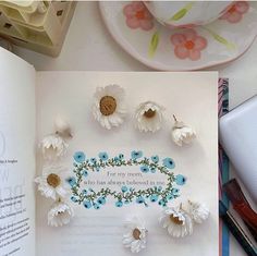 an open book with paper flowers on it