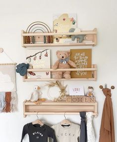 two wooden shelves with clothes and teddy bears on them, hanging from the wall next to other items