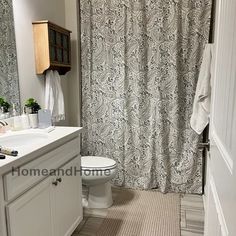 a bathroom with a toilet, sink and shower curtain in it's center area