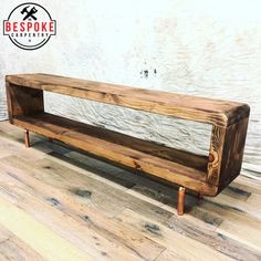 a wooden bench sitting on top of a hard wood floor next to a white wall