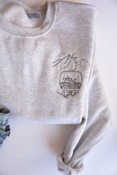 This embroidered chairlift couples crewneck is a great sweatshirt to cozy up in after a long day of skiing with your favorite ski buddy. It is soft and comfortable and perfect for those cold winter months. This pullover is the perfect addition to any ski lovers closet or as a gift for Valentines Day or an upcoming adventure or ski trip. This sweatshirt is unisex and tends to run true to size for men and runs a bit large for women. Want this in a different color? Send me a message and I would be happy to help!  These sweatshirts are made to order.  Made with 50% cotton, 50% polyester.  *WASHING INSTRUCTIONS*  - For the design on the shirt to last as long as possible, it is recommended to wash the shirt inside out with cold water and  either hang dry or tumble dry on low.  *CANCELLATIONS, RE Ski Hoodie Design, Ski Sweaters For Women, Casual Crew Neck Sweater For Ski Season, Heather Grey Winter Sweatshirt With Embroidered Logo, Heather Grey Embroidered Logo Sweatshirt For Winter, Winter Heather Grey Sweatshirt With Embroidered Logo, Casual Winter Sweater With Custom Embroidery, Casual Crew Neck Sweatshirt For Snowboarding, Casual Crew Neck Sweatshirt For Ski Season