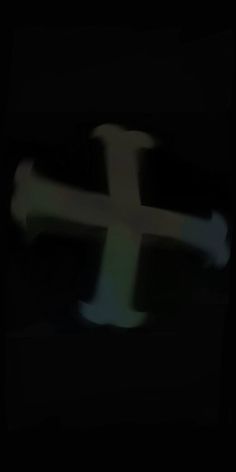 a blurry image of a cross on a black background with only one light visible