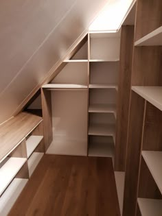 an attic bedroom with white shelves and wooden flooring