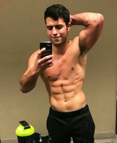 a shirtless man taking a selfie in front of a mirror with his cell phone