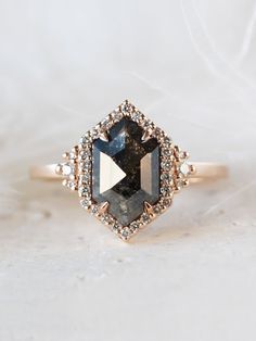 a close up of a ring with a black diamond in the center and white diamonds around it