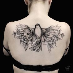 the back of a woman's shoulder with a bird and flowers tattoo on it