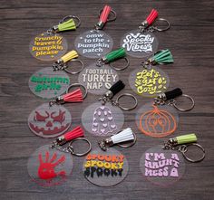 six key chains with different designs on them sitting on top of a wooden table next to each other