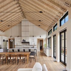 a large open concept living and dining room with wood floors, vaulted ceilings, white walls, and wooden flooring