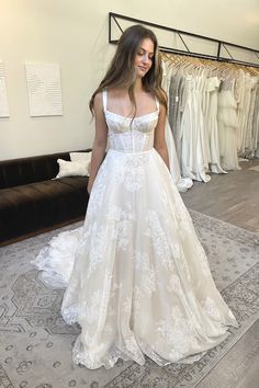 a woman standing in front of a dress on display at a bridal shop wearing a wedding gown