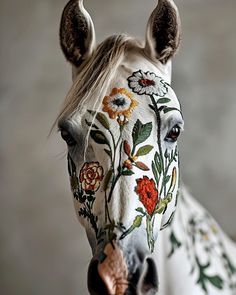 a white horse with flowers painted on it's face