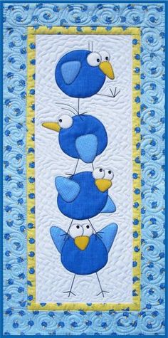 three blue birds with yellow beaks on a white and blue quilted wall hanging