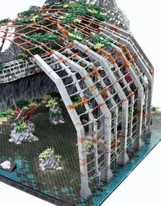 a building made out of legos on top of a white surface with mountains in the background