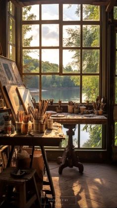 an artist's studio with large windows and lots of art supplies on the table